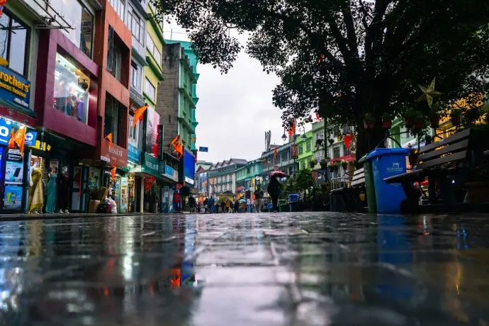 a wet street with people walking down it