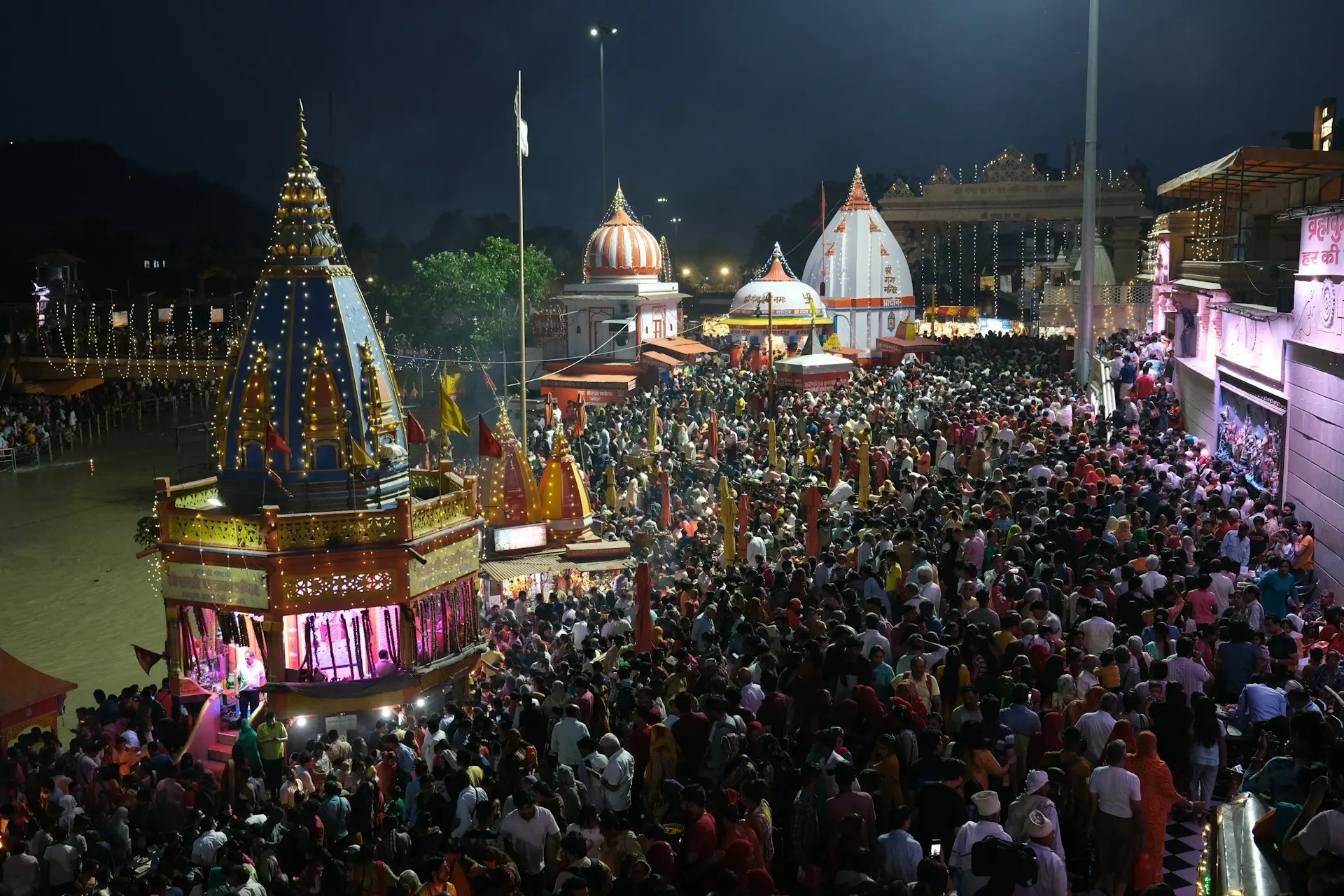 a crowd of people standing around a carnival at night