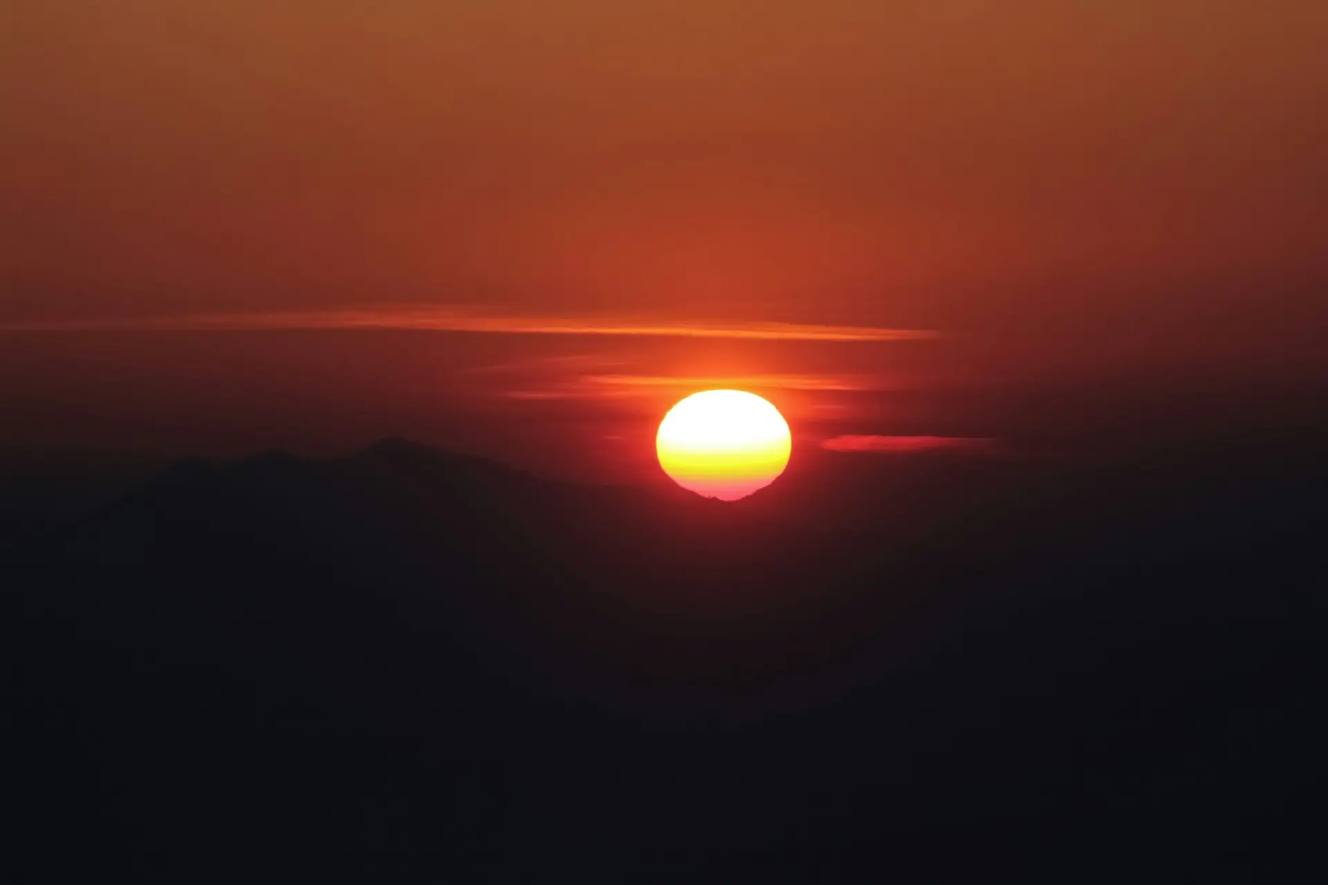 the sun is setting over a mountain range